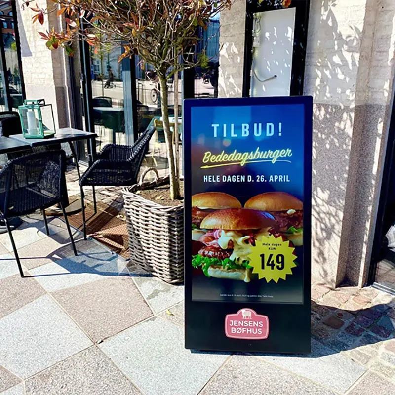 curbside advertising display playing a burger promotion near a roadside